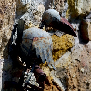 Un oiseau en métal accroché à un mur en pierres - France  - collection de photos clin d'oeil, catégorie clindoeil